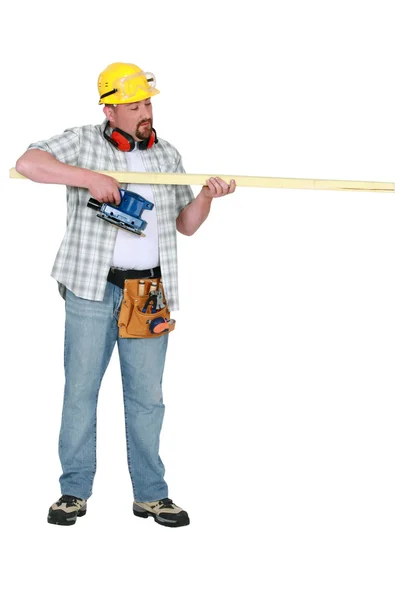 Construtor avaliando um pedaço de madeira — Fotografia de Stock