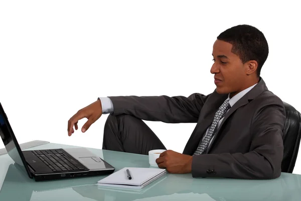 Jonge zakenman die op laptop zat met koffie in de hand — Stockfoto