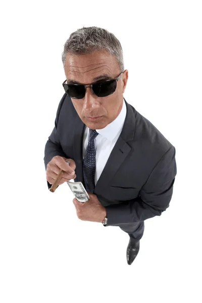 Businessman wearing sunglasses holding money and smoking a cigar — Stock Photo, Image