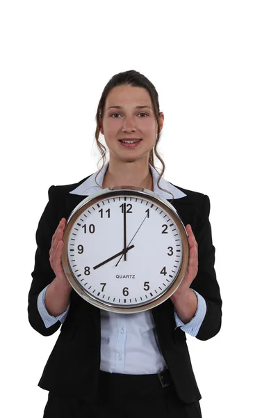 Woman in a suit holding a huge clock — Stock Photo, Image
