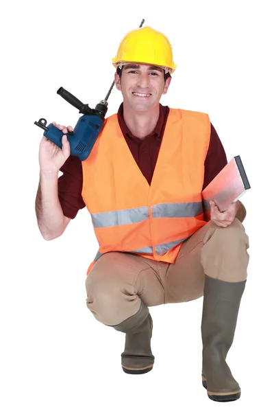 Worker kneeling with drill — Stockfoto