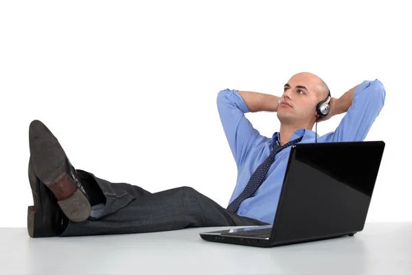 Empresario escuchando auriculares en su escritorio — Foto de Stock