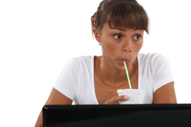 Woman drinking through straw at desk clipart