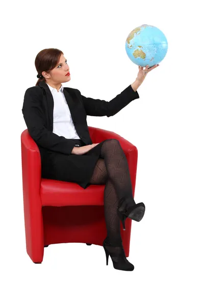 Geschäftsfrau im Sessel hält Globus — Stockfoto