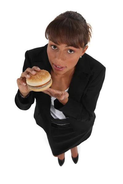 Businesswoman eating a hamburger — Stock Photo, Image