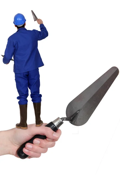 Man with a trowel standing on an arm with a trowel — Stock Photo, Image