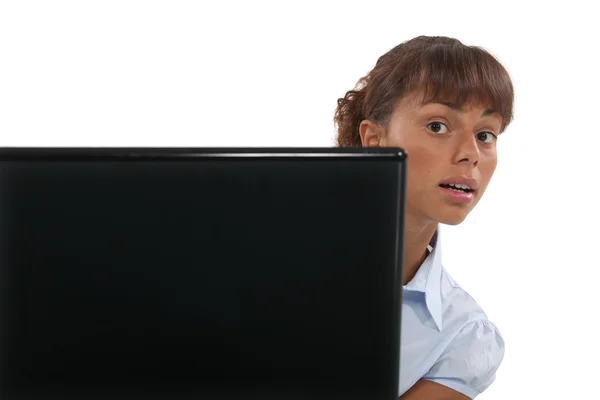 Woman peeking out from behind a laptop — Stock Photo, Image