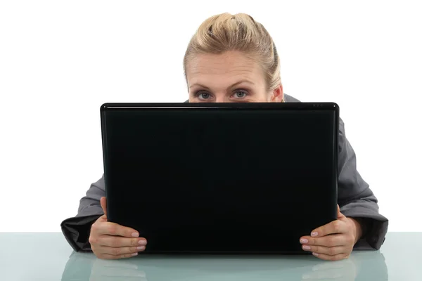 Blonde Büroangestellte versteckt sich hinter Laptop — Stockfoto