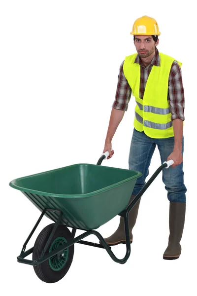 Unfriendly labourer pushing a wheelbarrow — Stock Photo, Image