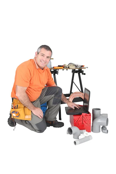 Labourer kneeling by laptop computer — Stock Photo, Image