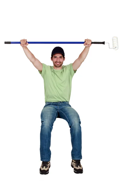 Tradesman sitting on an invisible object and holding up a paint roller — Stock Photo, Image