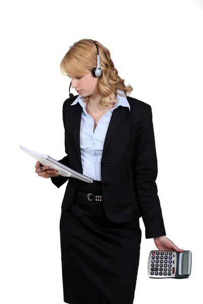 Portrait of blonde in suit with headset holding notepad and calculator — Stock Photo, Image