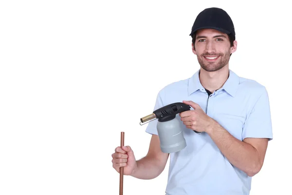 Young handsome plumber at work with copper pipe and tool — Stock Photo, Image