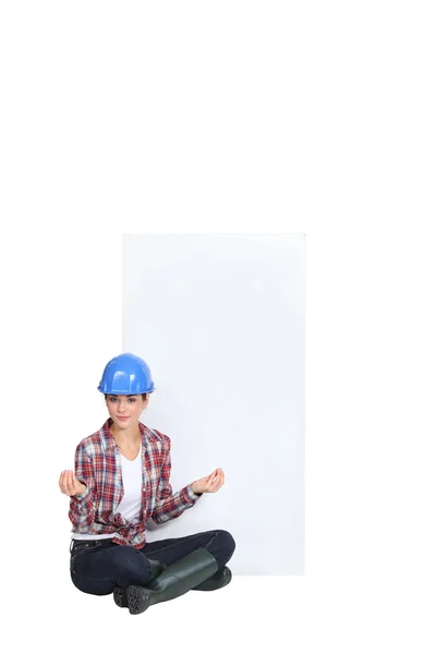 A female construction worker in the lotus position. — Stock Photo, Image
