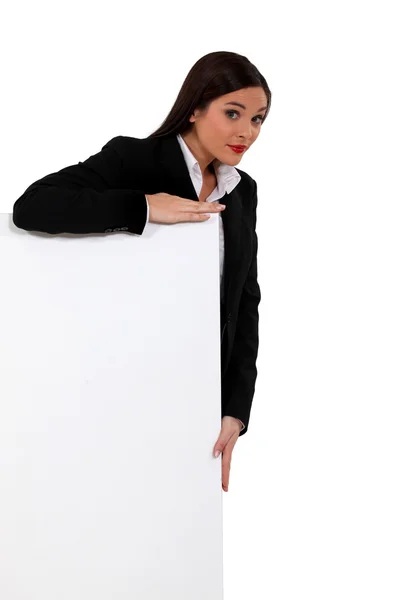 Businesswoman standing behind a white sign — Stock Photo, Image