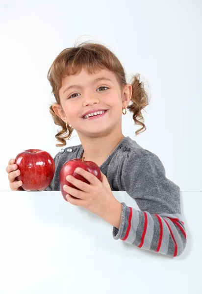 Маленькая девочка держит два яблока — стоковое фото
