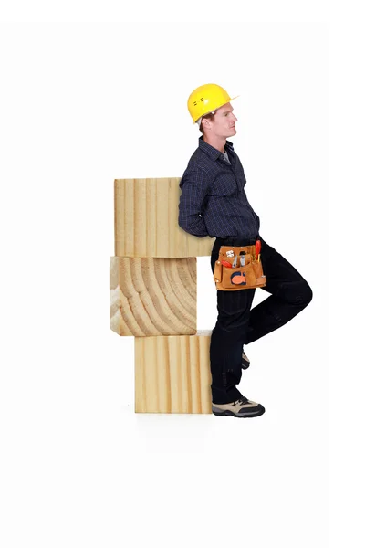 Carpinteiro inclinado contra blocos de madeira — Fotografia de Stock