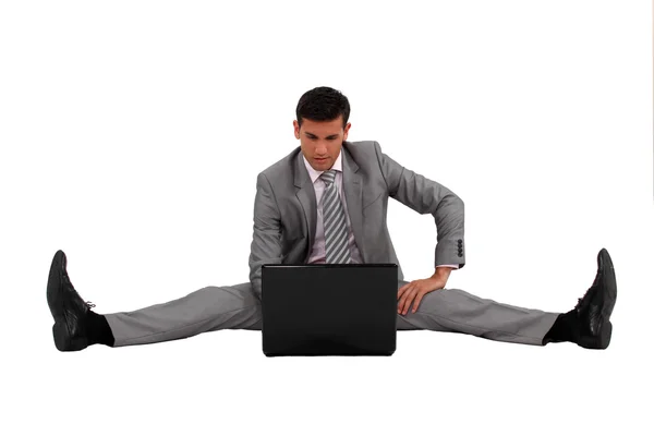 Affärsman med sin laptop med benen särade — Stockfoto