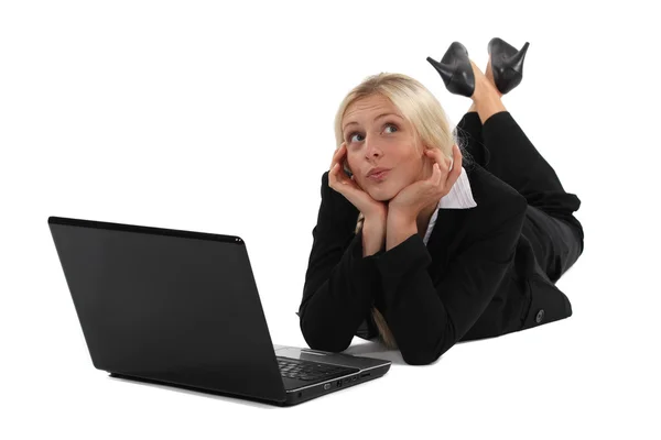 Distracted blond woman laying on floor with laptop — Stock Photo, Image