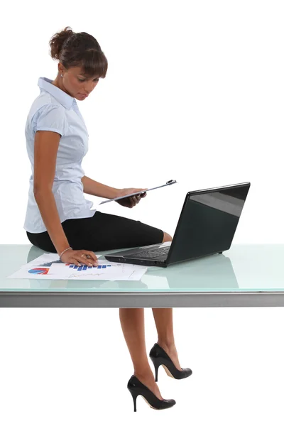 Donna seduta alla scrivania a guardare grafici — Foto Stock