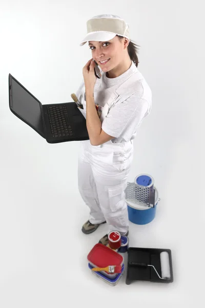 Vrouwelijke schilder met laptop en mobiele telefoon — Stockfoto