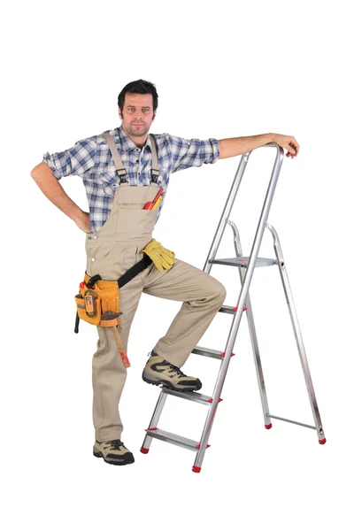 Trabalhador apoiado em uma escada isolada em fundo branco — Fotografia de Stock
