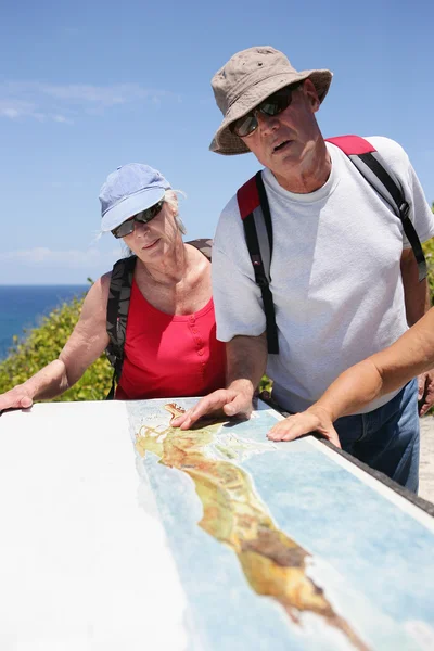 Turisté při pohledu na mapu na pobřeží — Stock fotografie