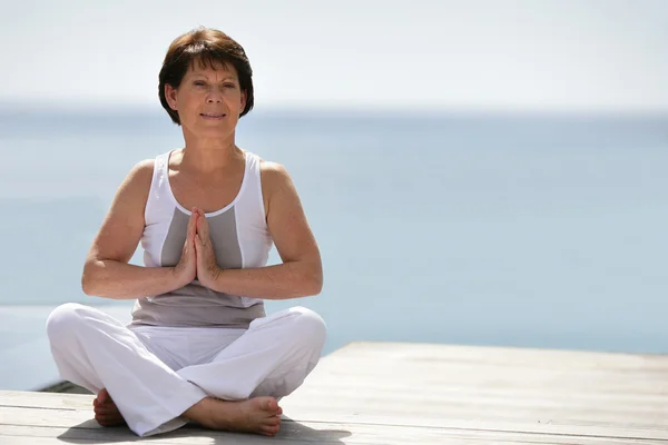 Woman practicing yoga by the ocean — Stock Photo, Image