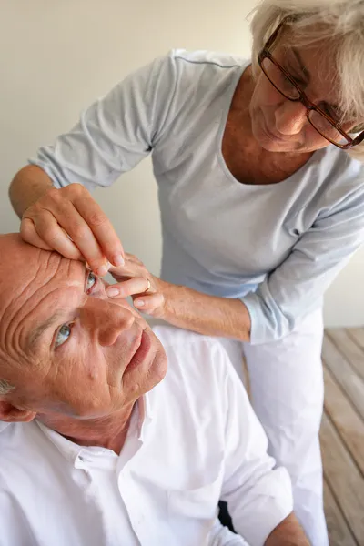 Wife helping husband with contact lenses — Stock Photo, Image