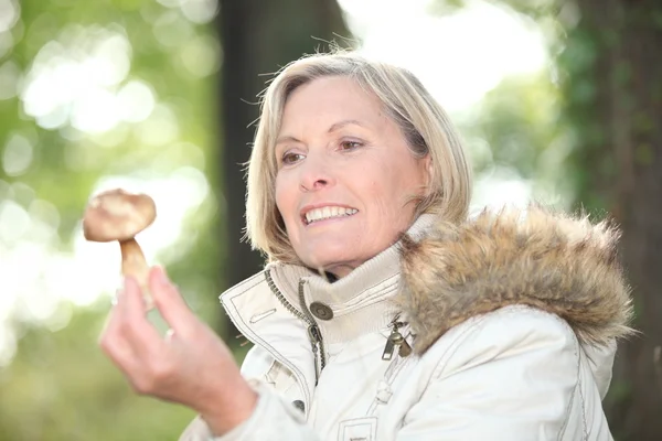 Mulher com um cogumelo em uma floresta — Fotografia de Stock