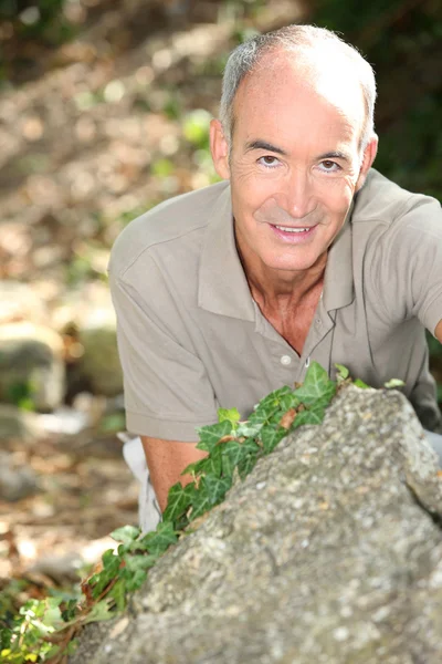Mannen på knä bakom en sten — Stockfoto