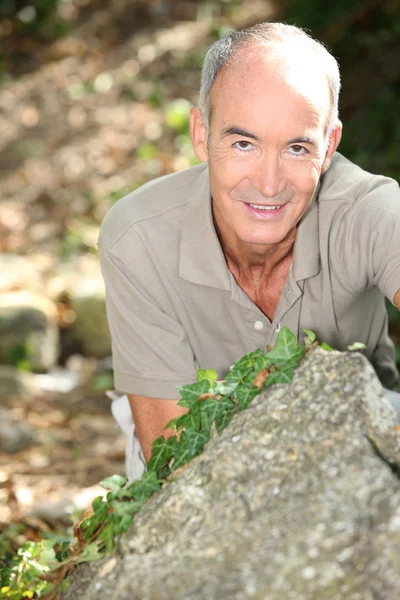 Man kneeling behind a boulder — Stock Photo, Image