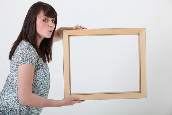 Brunette holding empty picture frame — Stock Photo, Image