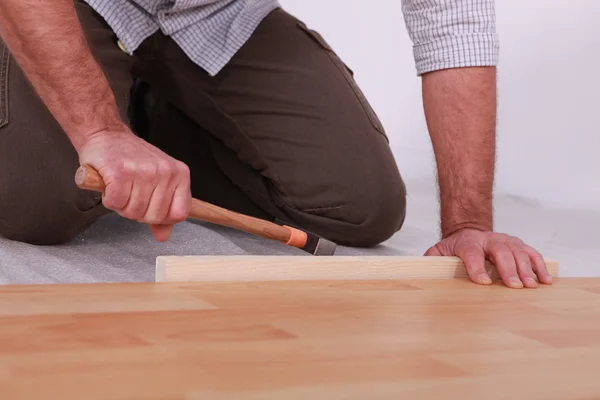 Man hammering laminate flooring into place — Stock Photo, Image
