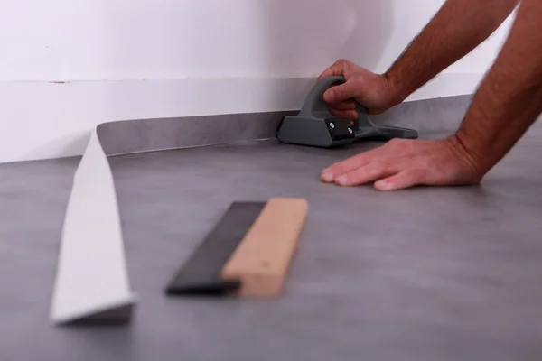 Man trimming linoleum against a skirting board — Stock Photo, Image