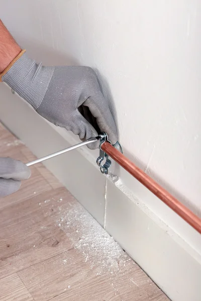 Worker fixing a pipe to a wall — Stock Photo, Image