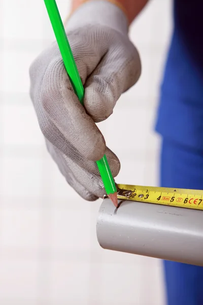 Trabajador marcando una medición en un tubo — Foto de Stock