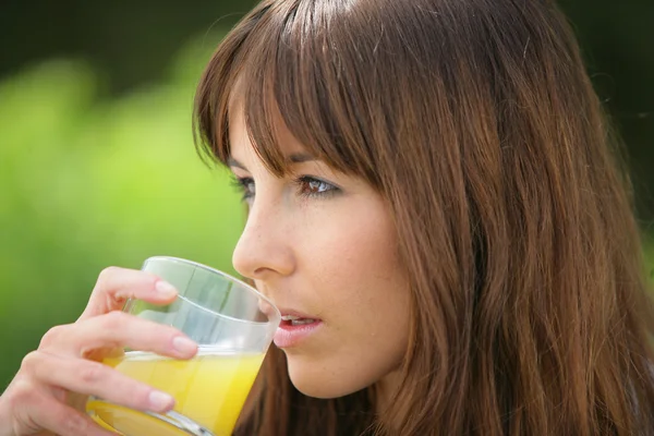 Žena pije pomerančový džus — Stock fotografie
