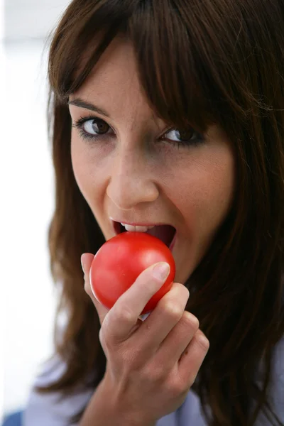 Brunette bijten in een tomaat — Stockfoto
