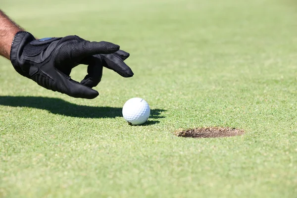 Golfeur frappant la balle dans le trou avec sa main — Photo