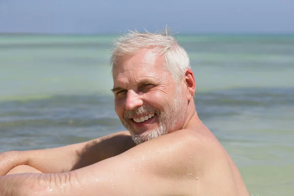Старший мужчина один на пляже — стоковое фото