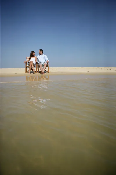 Couple sitting on a beach — Stock Photo, Image