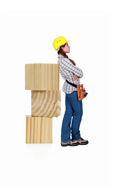 Female carpenter standing by large wooden blocks — Stock Photo, Image