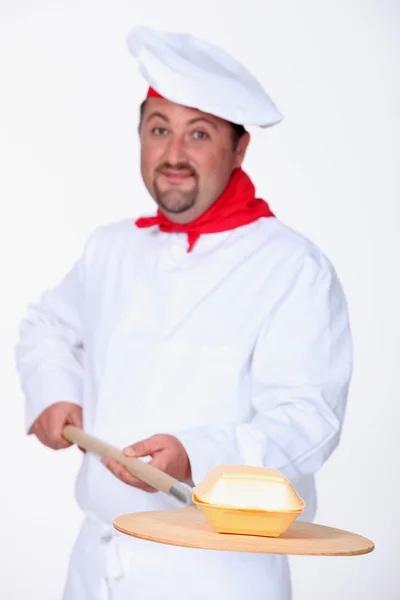 Um cozinheiro chefe segurando uma pá com um prato cremoso — Fotografia de Stock