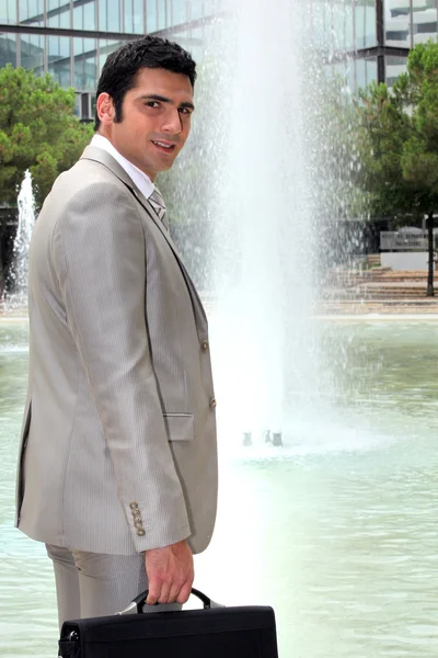 Affärsman som står framför en fontän — Stockfoto