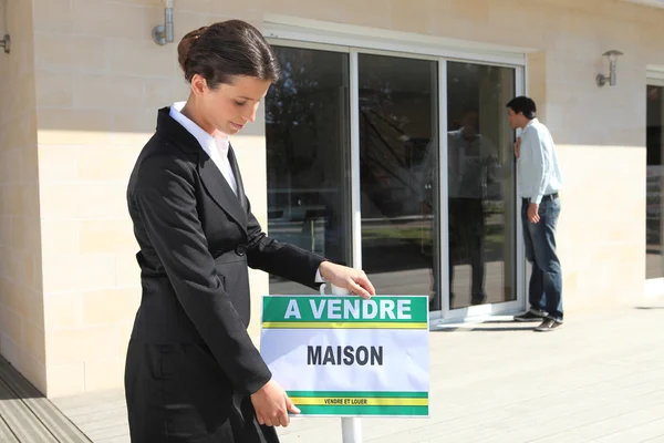 Femme plaçant la maison à vendre signe — Photo