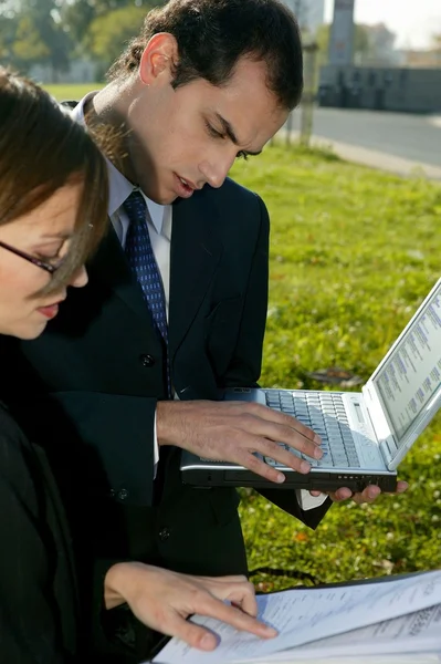 Twee bedrijf met behulp van een laptop in de buitenlucht — Stockfoto