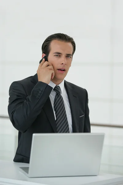 Uomo d'affari che utilizza un telefono cellulare e un computer portatile — Foto Stock