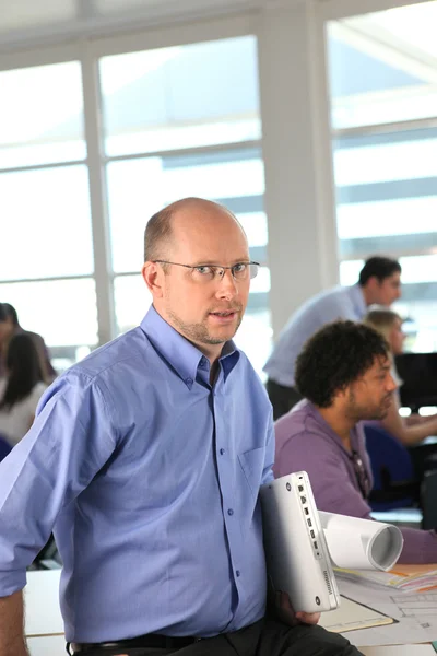 Man with rolls of drawings in an office — Stock Photo, Image