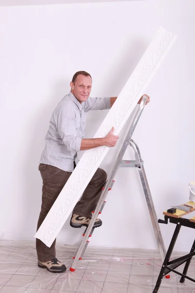 Man putting up coving using a stepladder — Stock Photo, Image